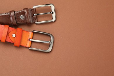Photo of Two leather belts on pale brown background, flat lay. Space for text