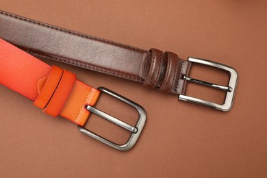 Photo of Two leather belts on pale brown background, flat lay