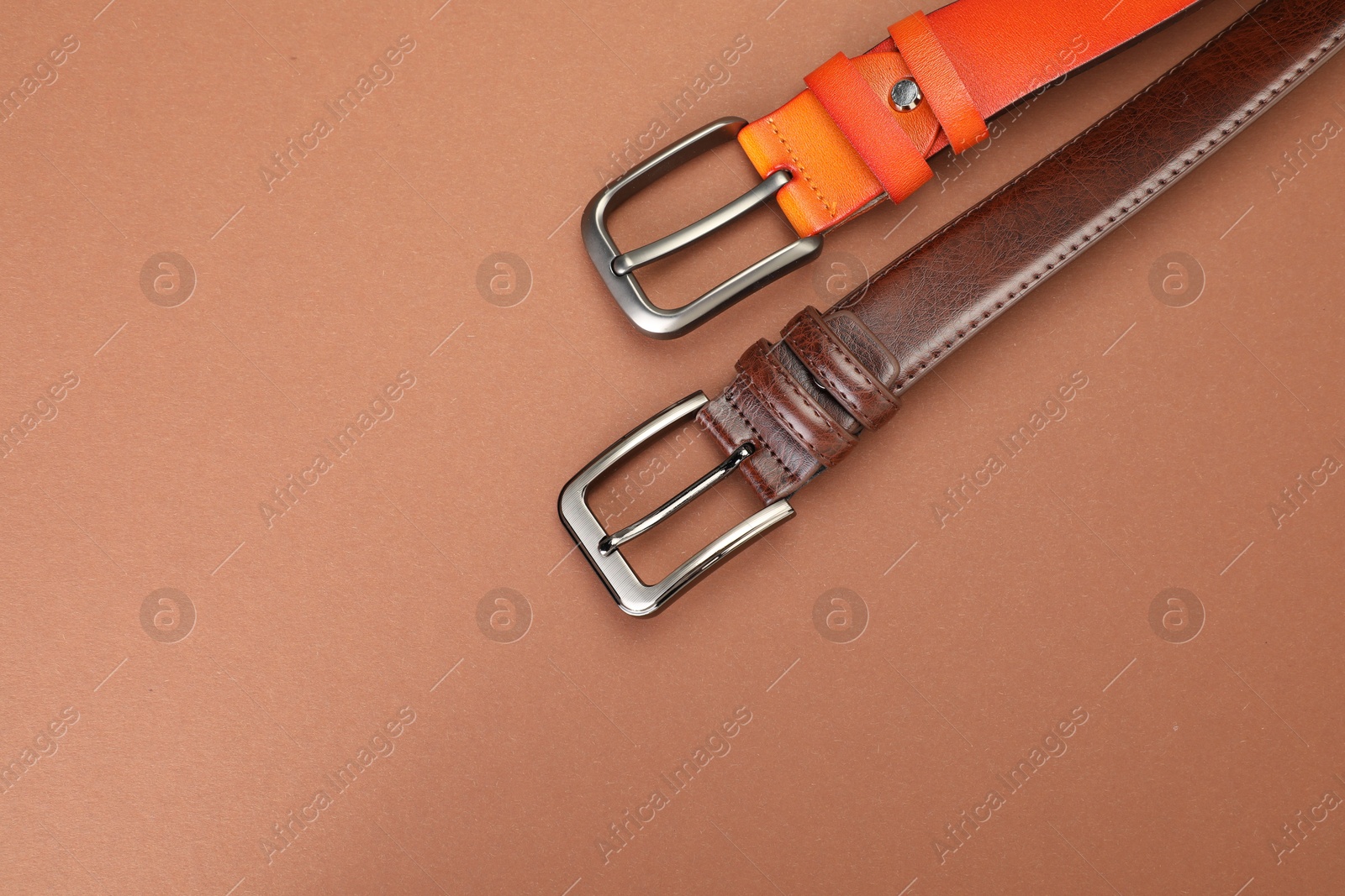 Two leather belts on pale brown background, flat lay. Space for text Photo of Two leather belts on pale brown background, flat lay. Space for text