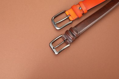 Photo of Two leather belts on pale brown background, flat lay. Space for text