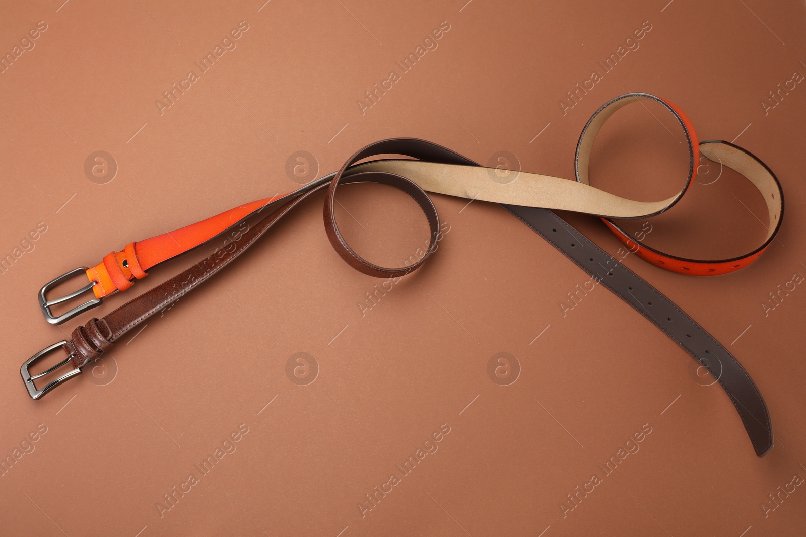 Two leather belts on pale brown background, flat lay Photo of Two leather belts on pale brown background, flat lay