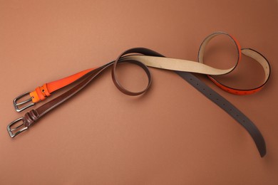 Photo of Two leather belts on pale brown background, flat lay
