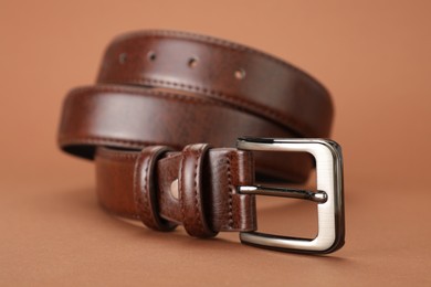 Photo of One leather belt on pale brown background, closeup