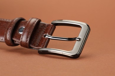 Photo of One leather belt on pale brown background, closeup