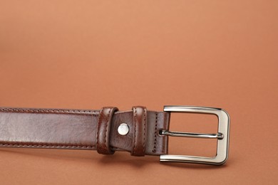 Photo of One leather belt on pale brown background, closeup