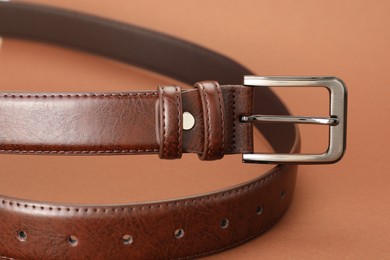 Photo of One leather belt on pale brown background, closeup