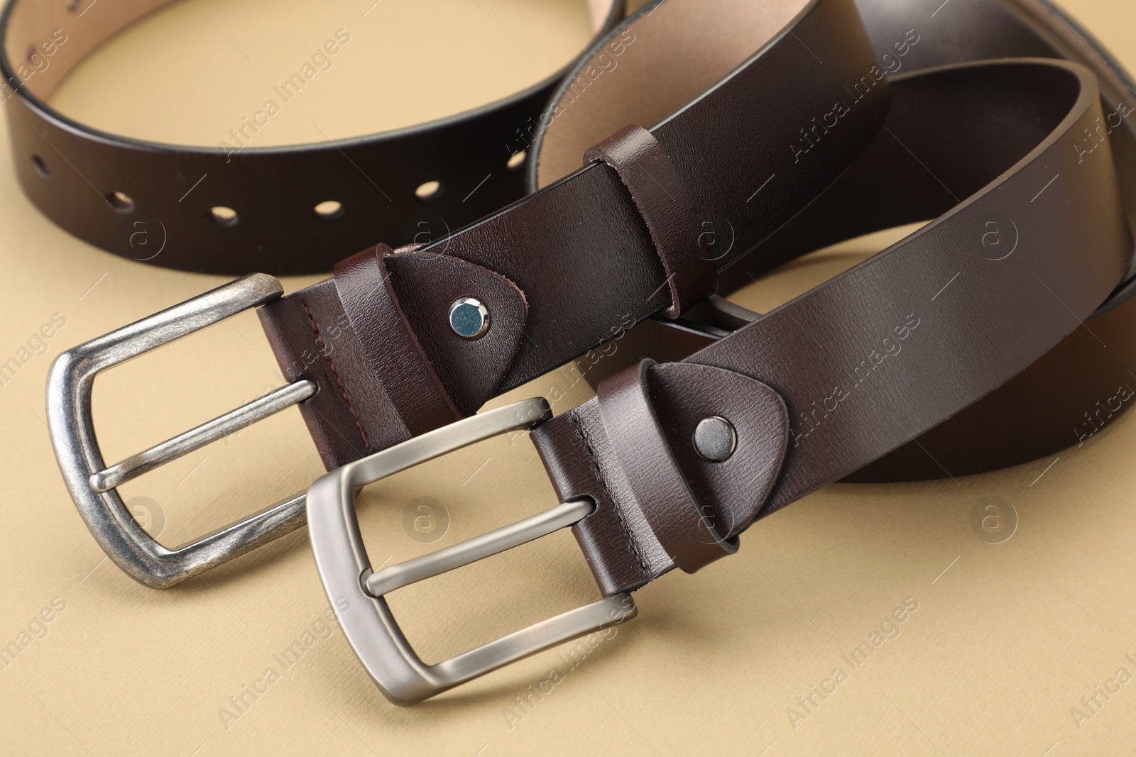 Two leather belts on beige background, closeup Photo of Two leather belts on beige background, closeup