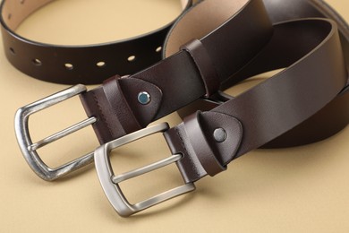 Photo of Two leather belts on beige background, closeup