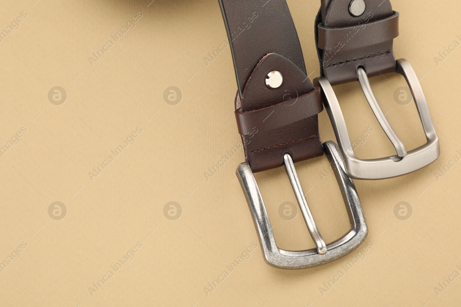 Two leather belts on beige background, above view. Space for text Photo of Two leather belts on beige background, above view. Space for text