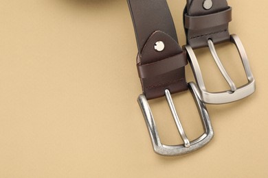 Photo of Two leather belts on beige background, above view. Space for text