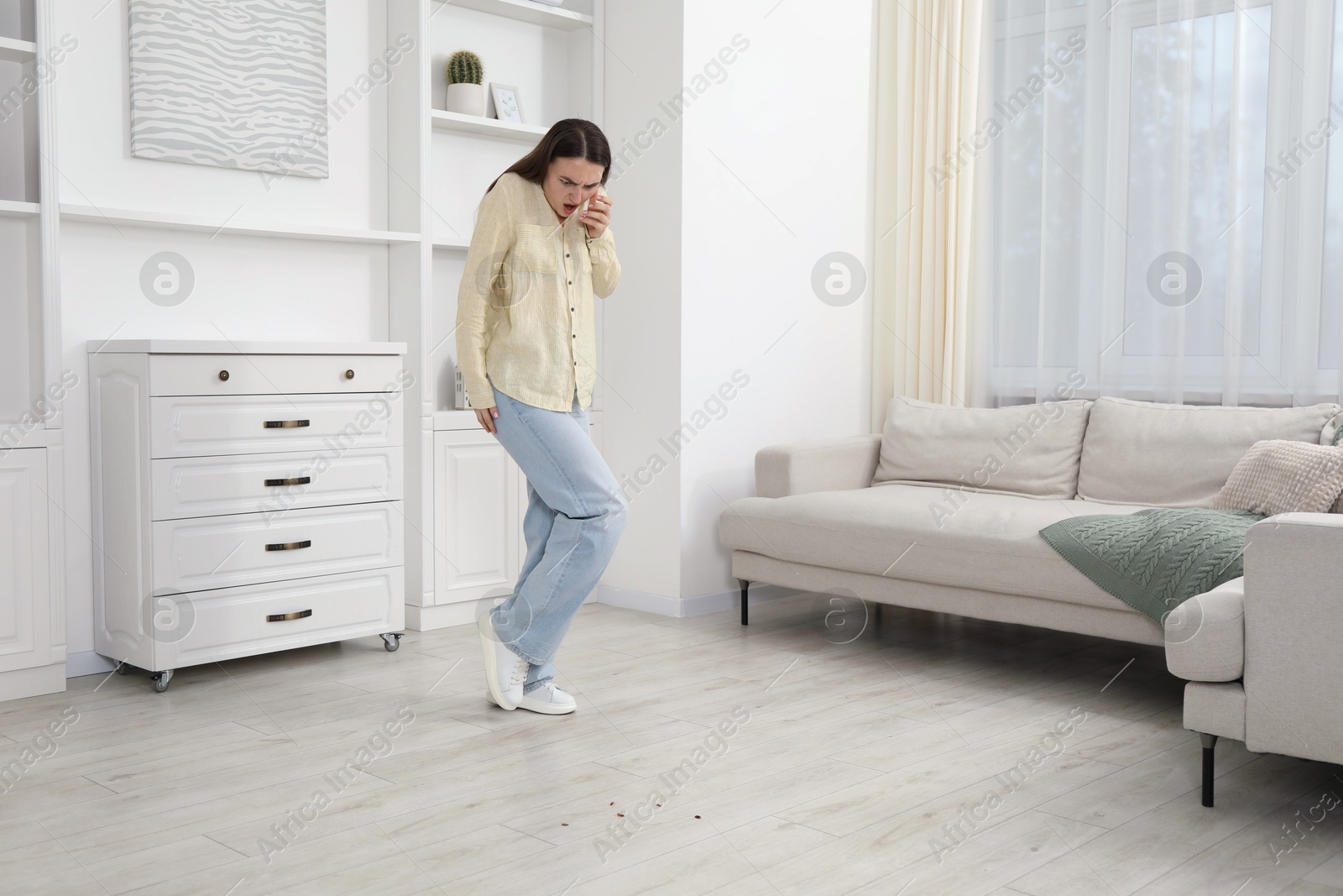 Emotional young woman looking in disgust at cockroaches on floor indoors. Pest problem Photo of Emotional young woman looking in disgust at cockroaches on floor indoors. Pest problem