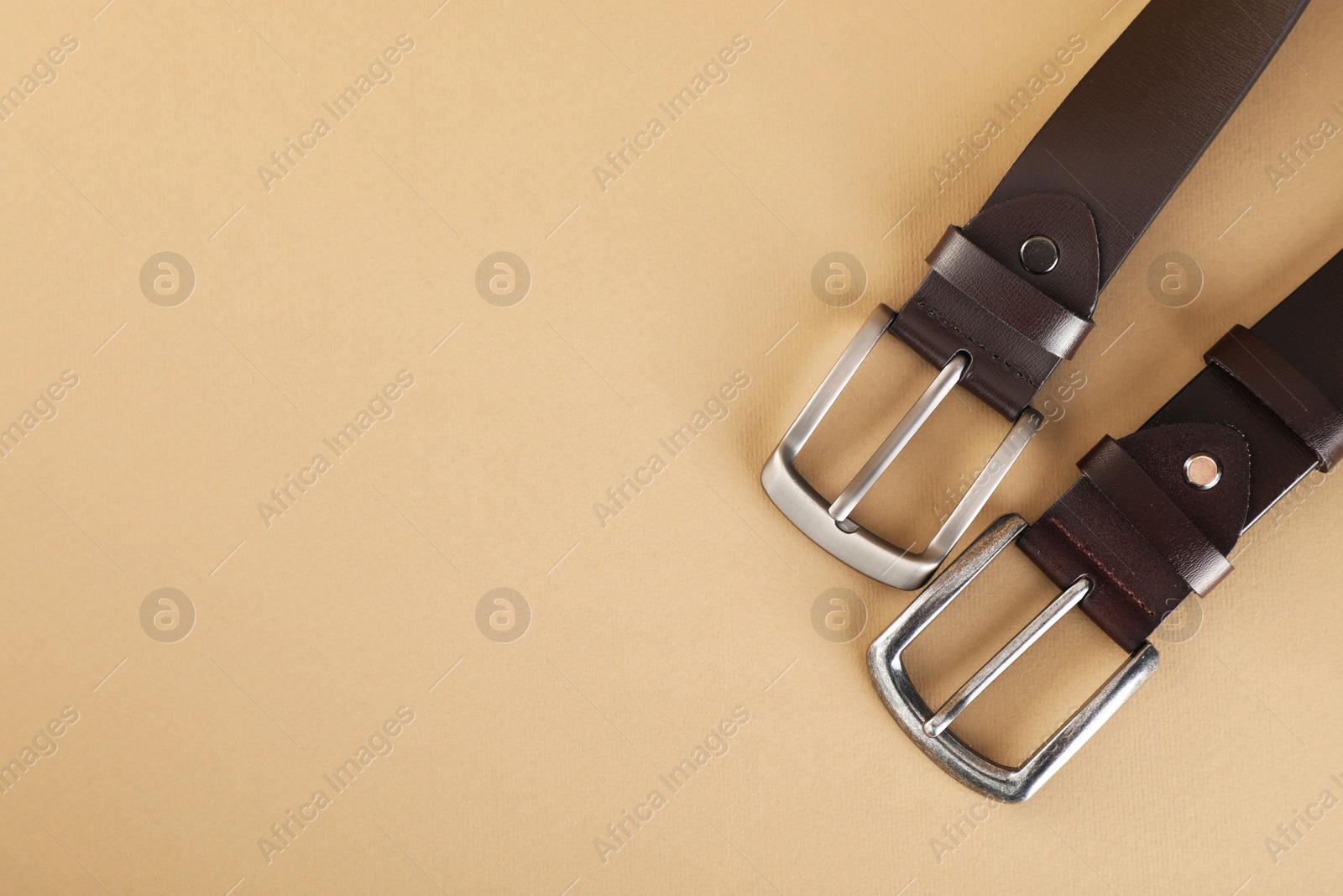 Two leather belts on beige background, flat lay. Space for text Photo of Two leather belts on beige background, flat lay. Space for text