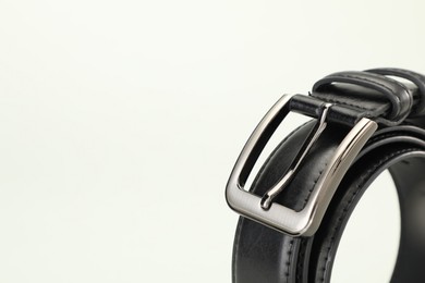 Photo of One black leather belt on white background, closeup. Space for text