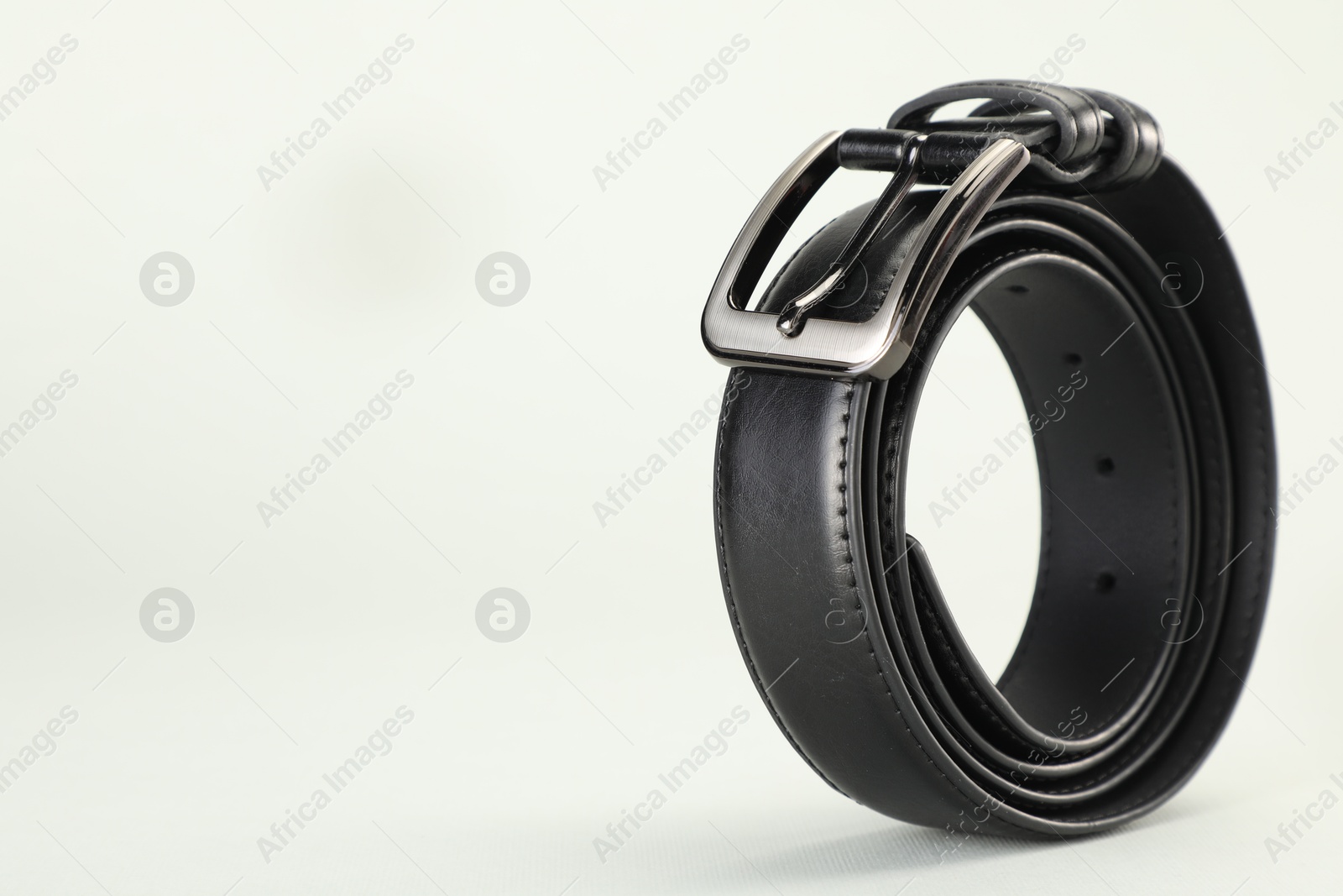 One black leather belt on white background, closeup. Space for text Photo of One black leather belt on white background, closeup. Space for text