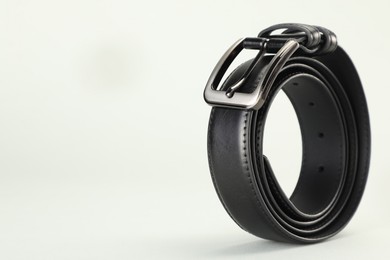 Photo of One black leather belt on white background, closeup. Space for text