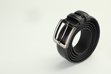 Photo of One black leather belt on white background, closeup. Space for text