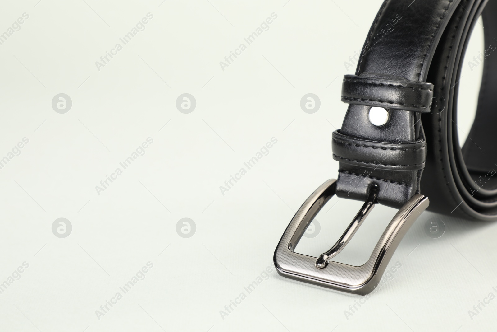One black leather belt on white background, closeup. Space for text Photo of One black leather belt on white background, closeup. Space for text