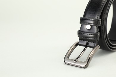 Photo of One black leather belt on white background, closeup. Space for text