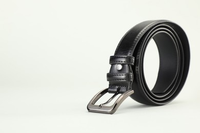 Photo of One black leather belt on white background, closeup. Space for text