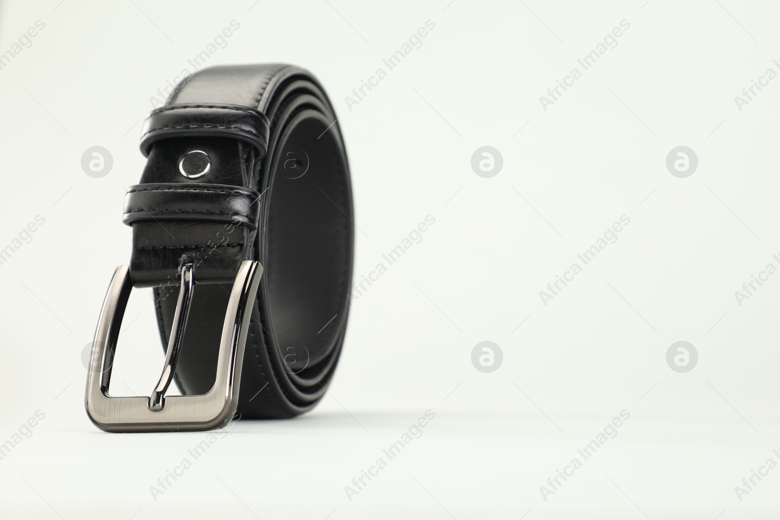 One black leather belt on white background, closeup. Space for text Photo of One black leather belt on white background, closeup. Space for text