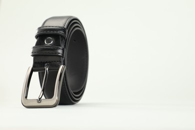 Photo of One black leather belt on white background, closeup. Space for text