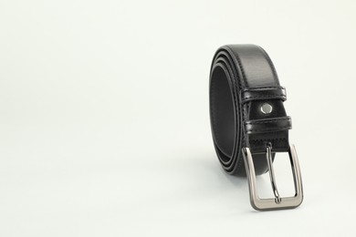 Photo of One black leather belt on white background, closeup. Space for text