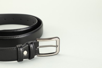 Photo of One black leather belt on white background, closeup. Space for text