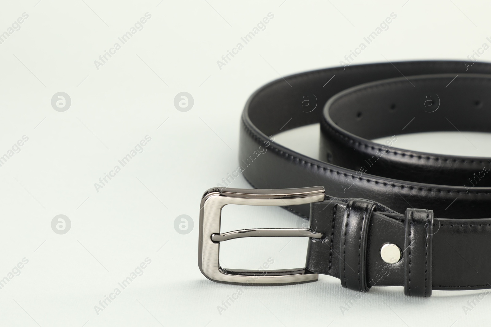 One black leather belt on white background, closeup. Space for text Photo of One black leather belt on white background, closeup. Space for text