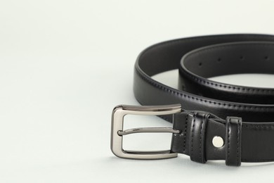 Photo of One black leather belt on white background, closeup. Space for text