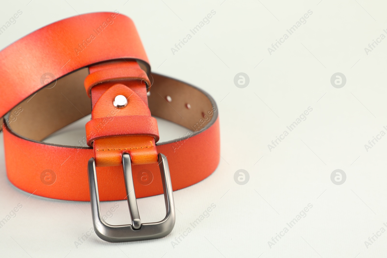 One orange leather belt on white background, closeup. Space for text Photo of One orange leather belt on white background, closeup. Space for text