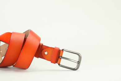 Photo of One orange leather belt on white background, closeup. Space for text