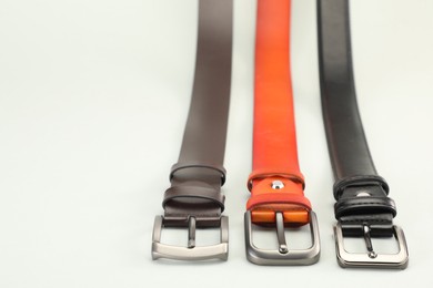 Photo of Three leather belts on white background, closeup. Space for text