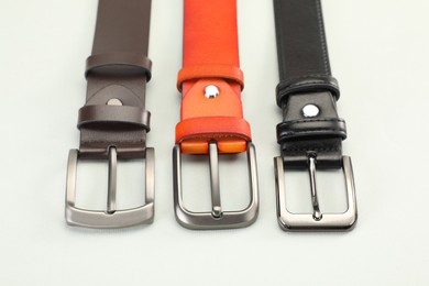Photo of Three leather belts on white background, above view