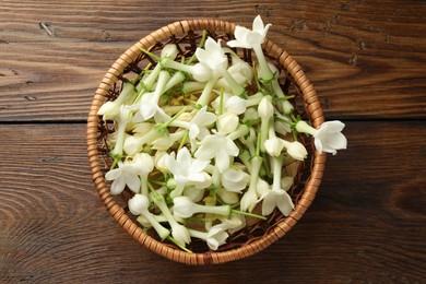 Photo of Wicker bowl with jasmine flowers on wooden table, top view