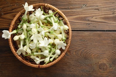Photo of Wicker bowl with jasmine flowers on wooden table, top view. Space for text