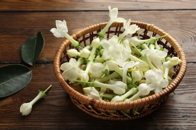 Photo of Wicker bowl with jasmine flowers on wooden table, closeup
