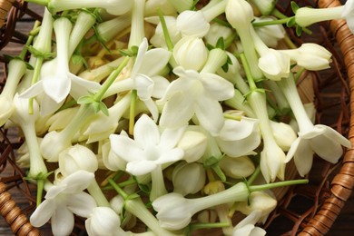 Photo of Wicker bowl with jasmine flowers on wooden table, top view