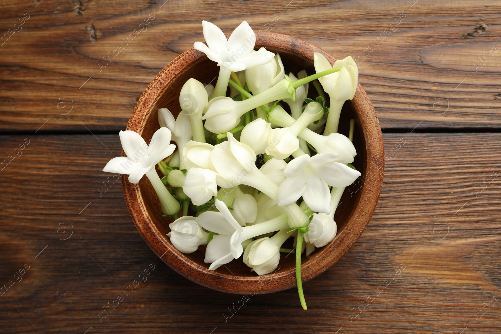 Bowl with jasmine flowers on wooden table, top view Photo of Bowl with jasmine flowers on wooden table, top view