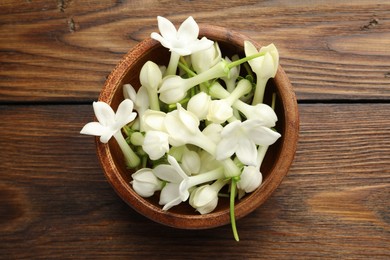 Photo of Bowl with jasmine flowers on wooden table, top view