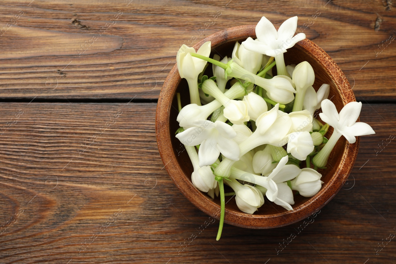 Bowl with jasmine flowers on wooden table, top view. Space for text Photo of Bowl with jasmine flowers on wooden table, top view. Space for text