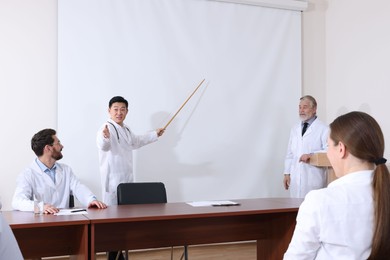 Photo of Doctors giving lecture near projection screen in conference room
