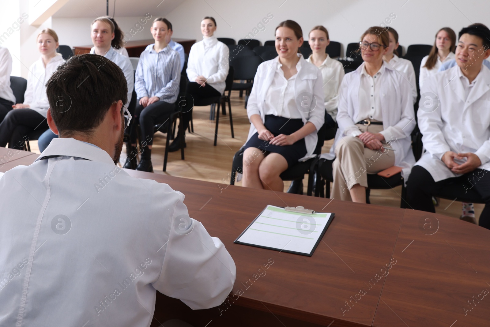 Photo of Senior doctor having discussion with audience during medical conference in meeting room