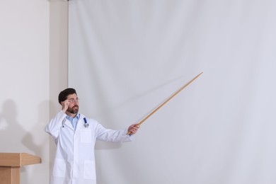 Photo of Doctor giving lecture in conference room with projection screen