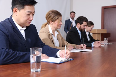 Photo of Business conference. People working at wooden table in meeting room