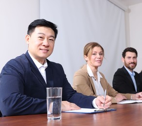 Photo of Business conference. People working at wooden table in meeting room