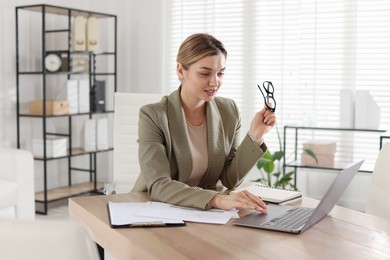 Photo of Professional banker working on laptop at desk in office