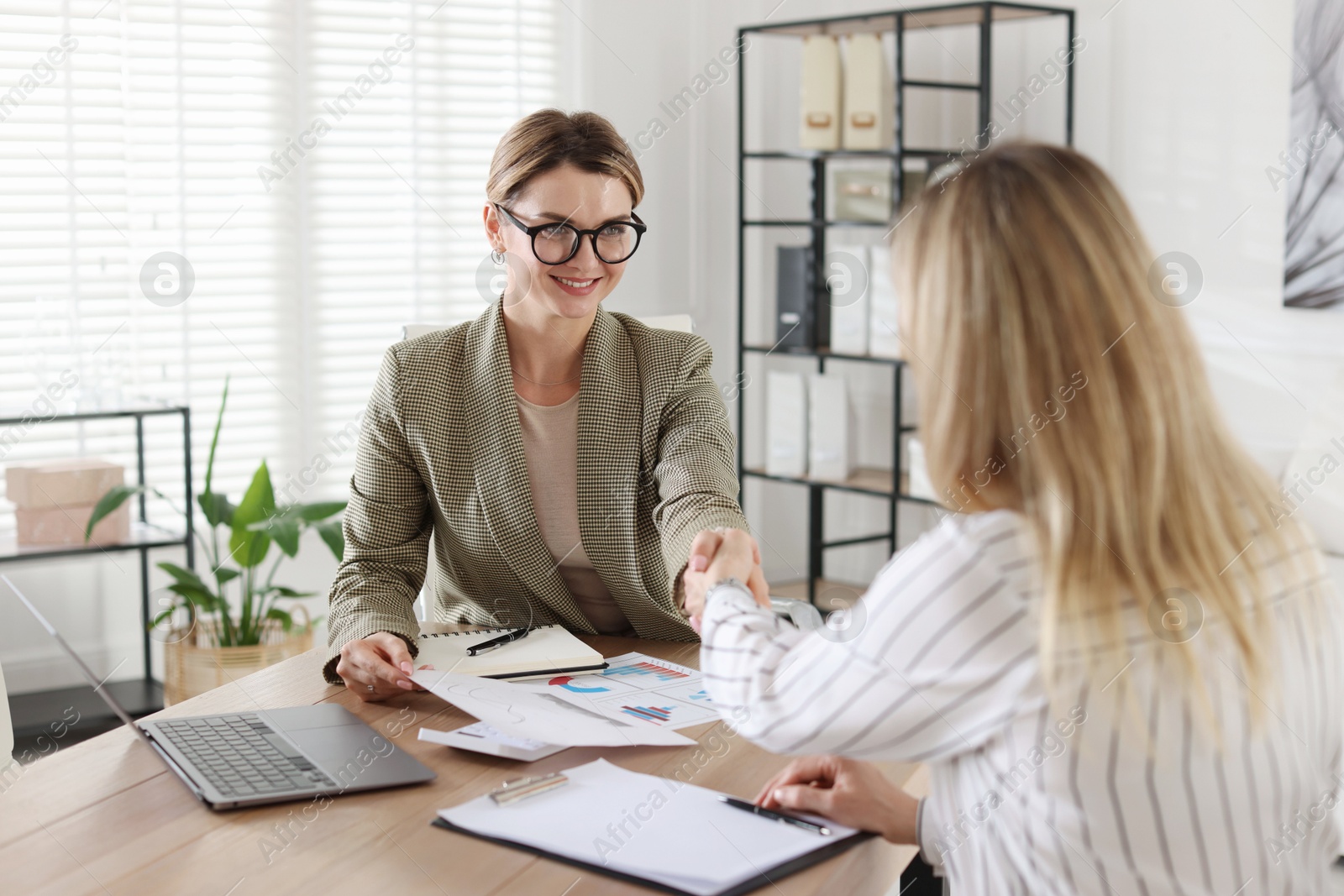 Woman shaking hands with banker during meeting in office Photo of Woman shaking hands with banker during meeting in office
