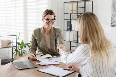 Photo of Woman shaking hands with banker during meeting in office