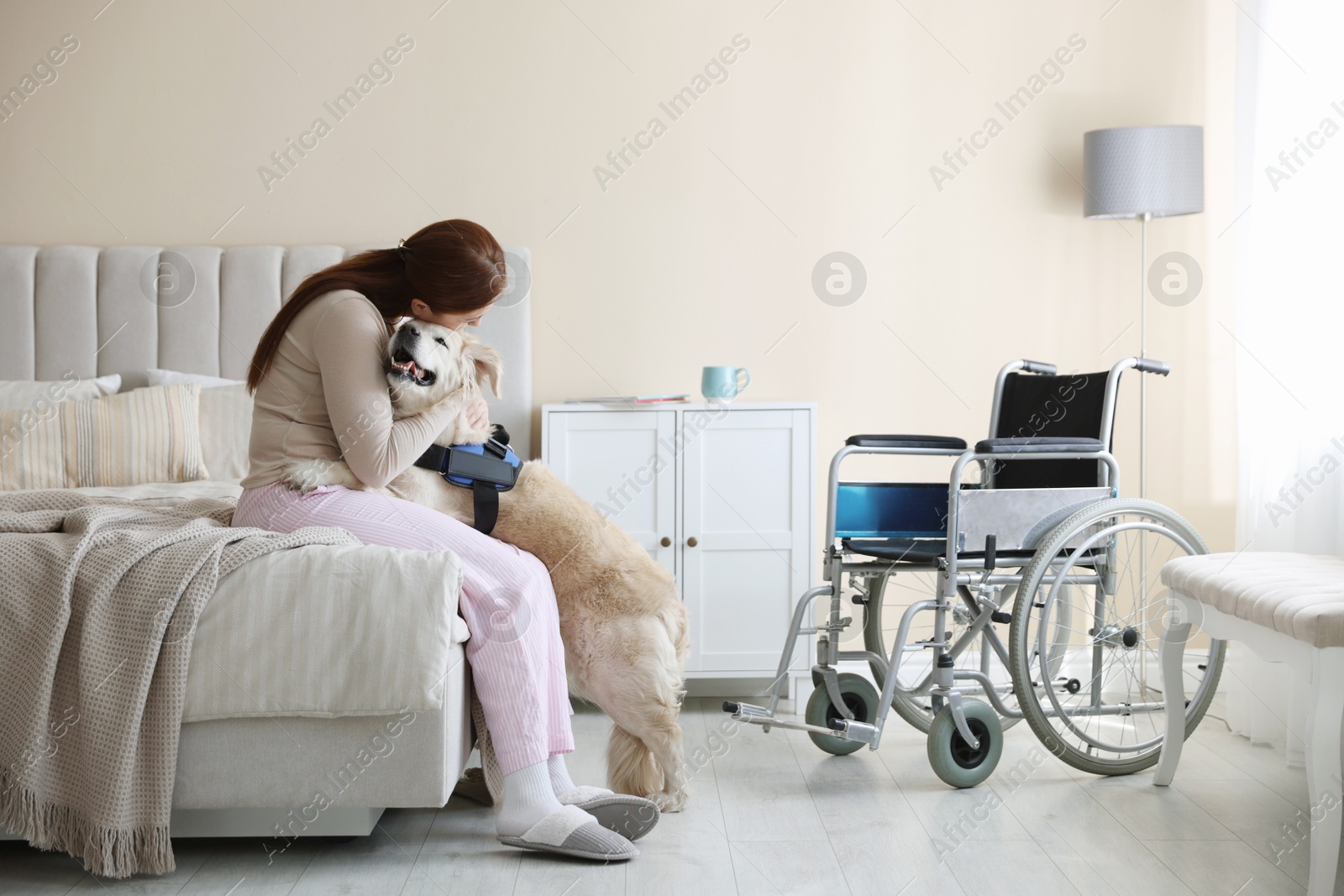 Woman with disability hugging her service dog at home Photo of Woman with disability hugging her service dog at home
