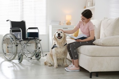 Photo of Girl with disability reading book and her service dog at home